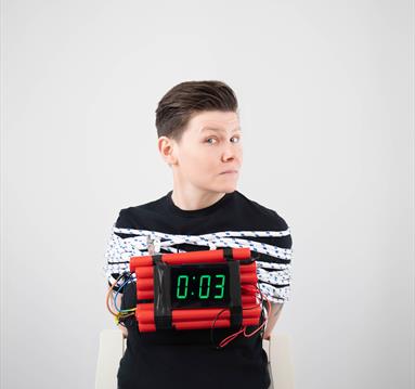 Image of Grace Petrie bound by ropes and holding a bomb that only has 3 seconds before it will detonate.