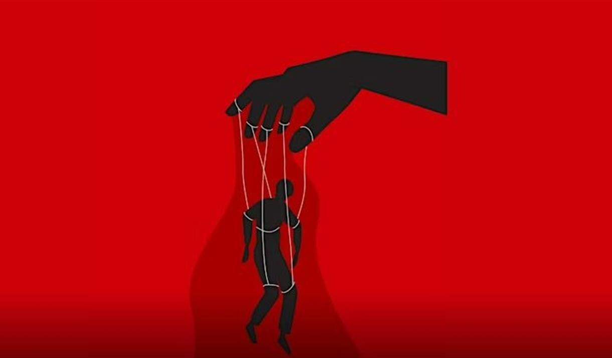 a red backdrop with a hand controlling a person posed as a puppet