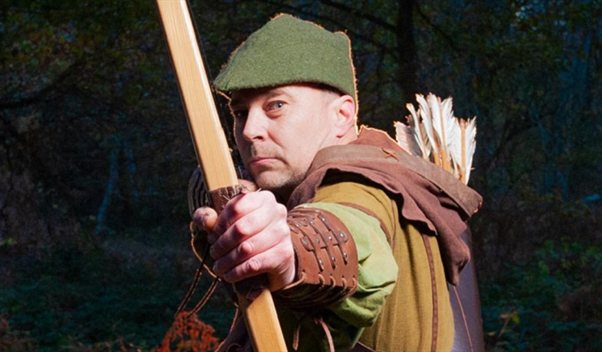 man dressed as robin hood doing archery