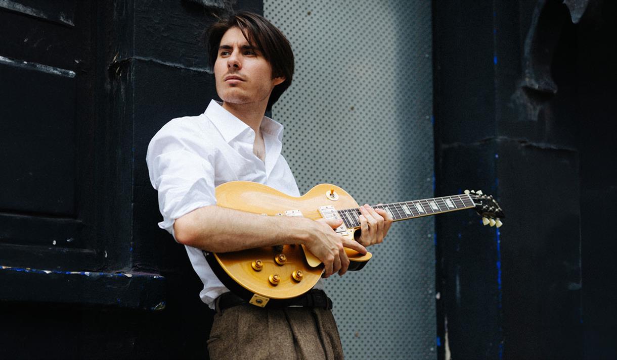 image of connor selby with his guitar
