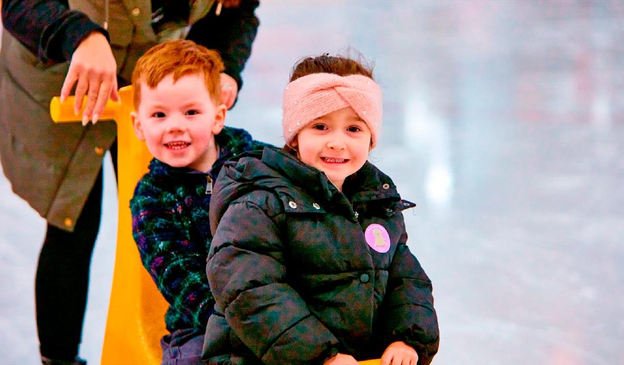 Photo of two young kids enjoying an ice-skating session using ice equipment