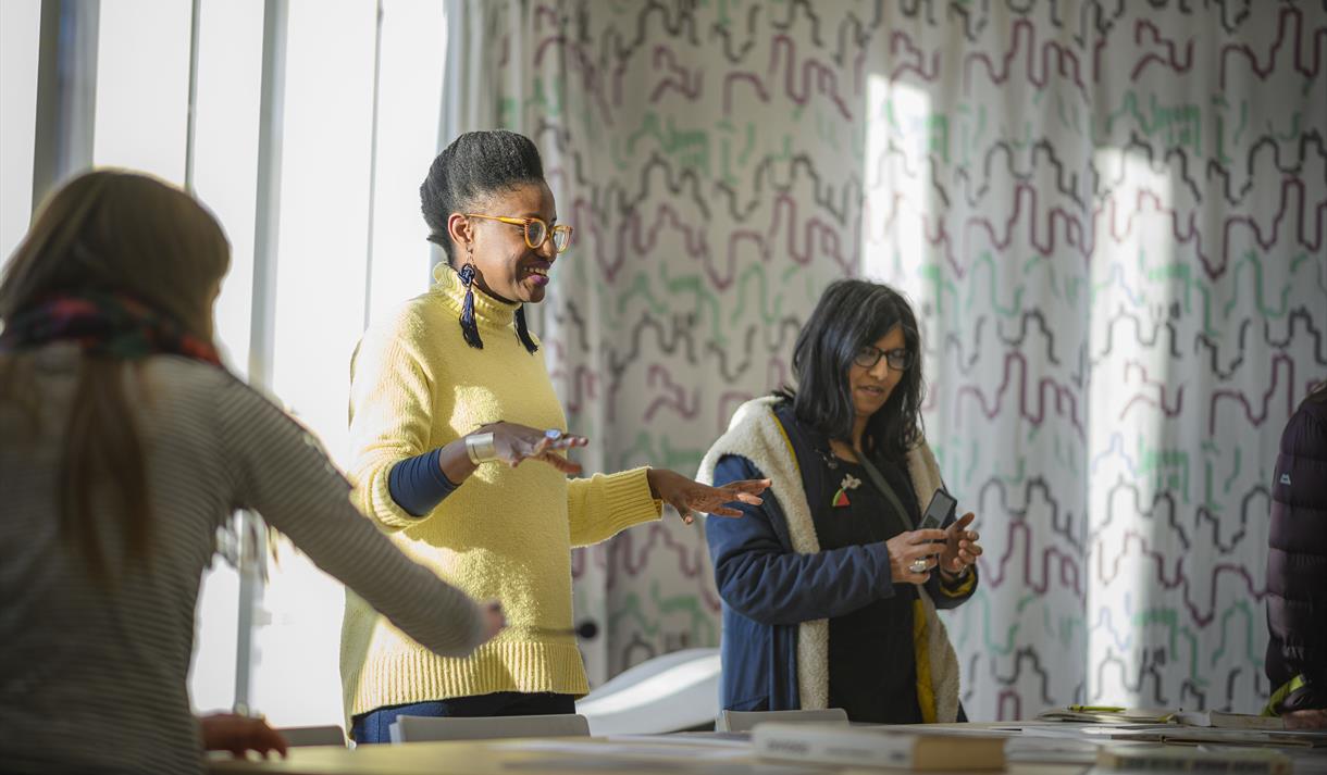 Three people standing round a table in front of a closed curtain