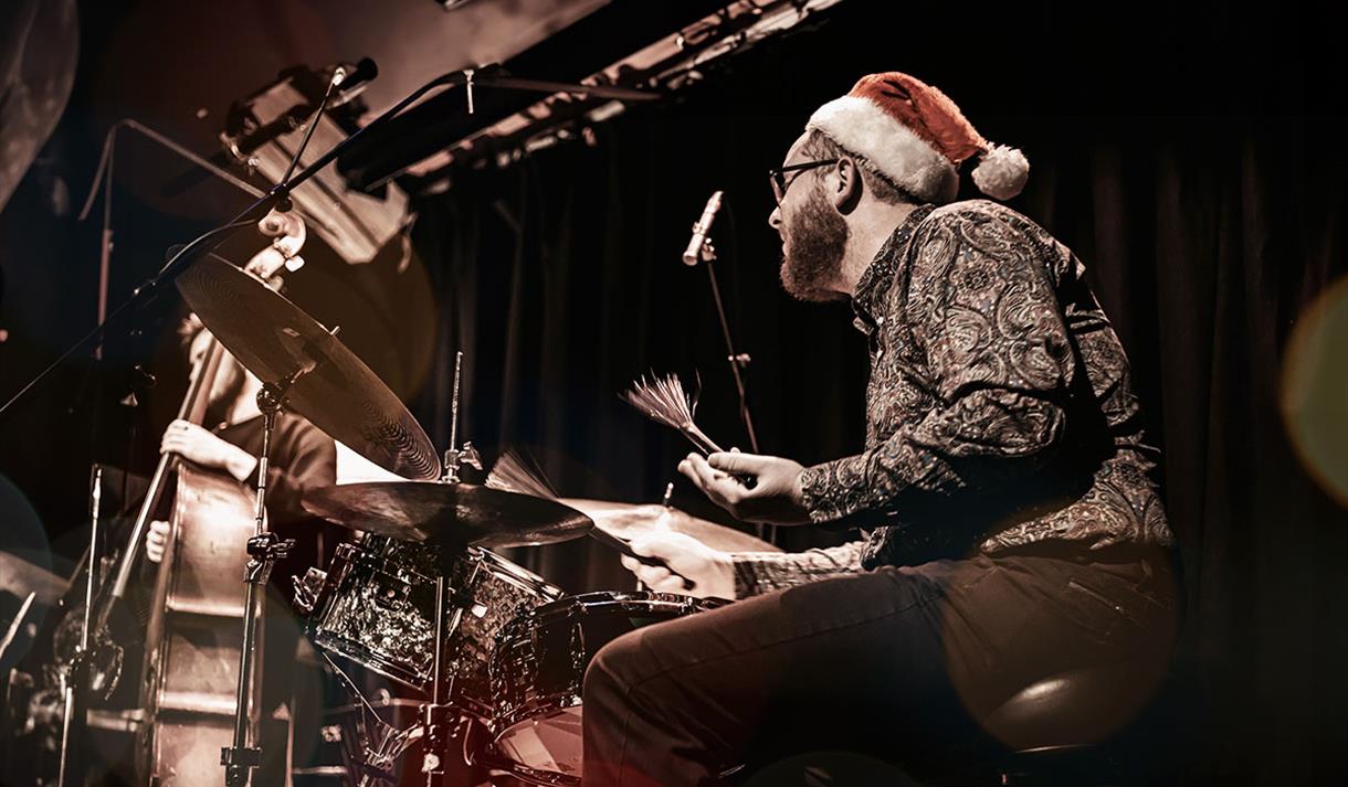 Photo of a man in a santa hat playing the drums