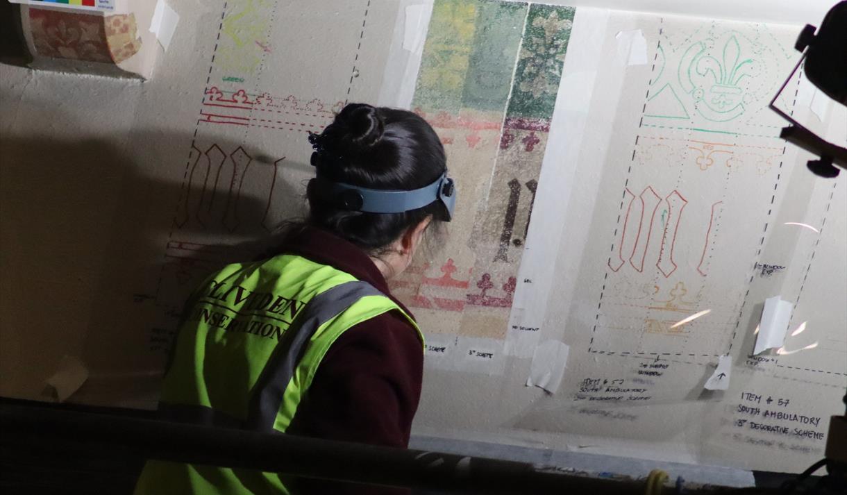 Photo of a person in a hi-via vest looking at design blueprints