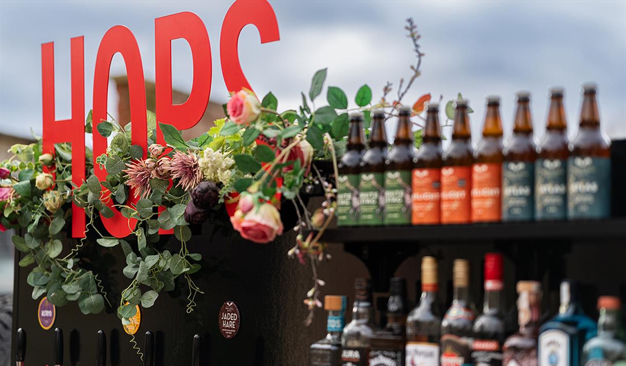 Image including locally brewed bottled beers and a floral display