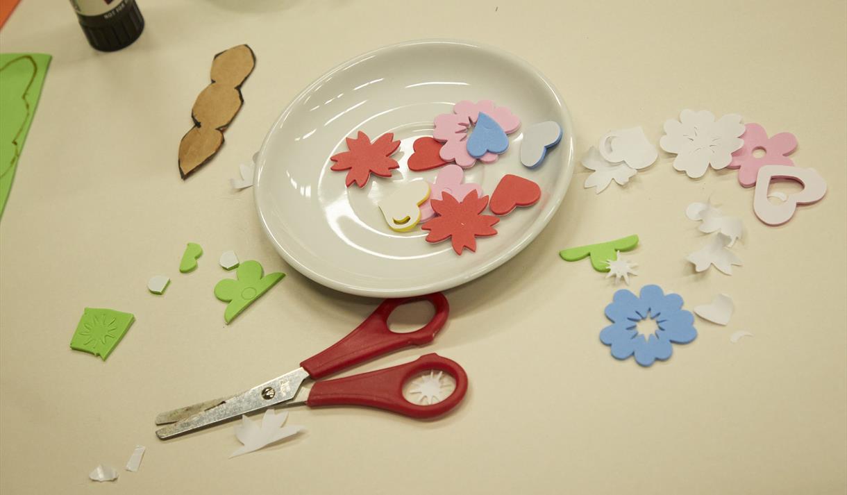 Photo of a crafts table with cut out bits of paper