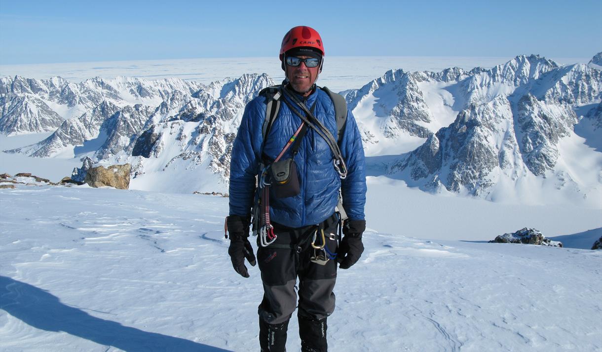 Photo of mountaineer Simon Yates on top of a snow covered mountain.