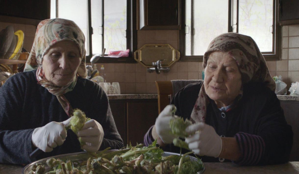 Photo of a still from the film, showing two women preparing vegetables at a kitchen table