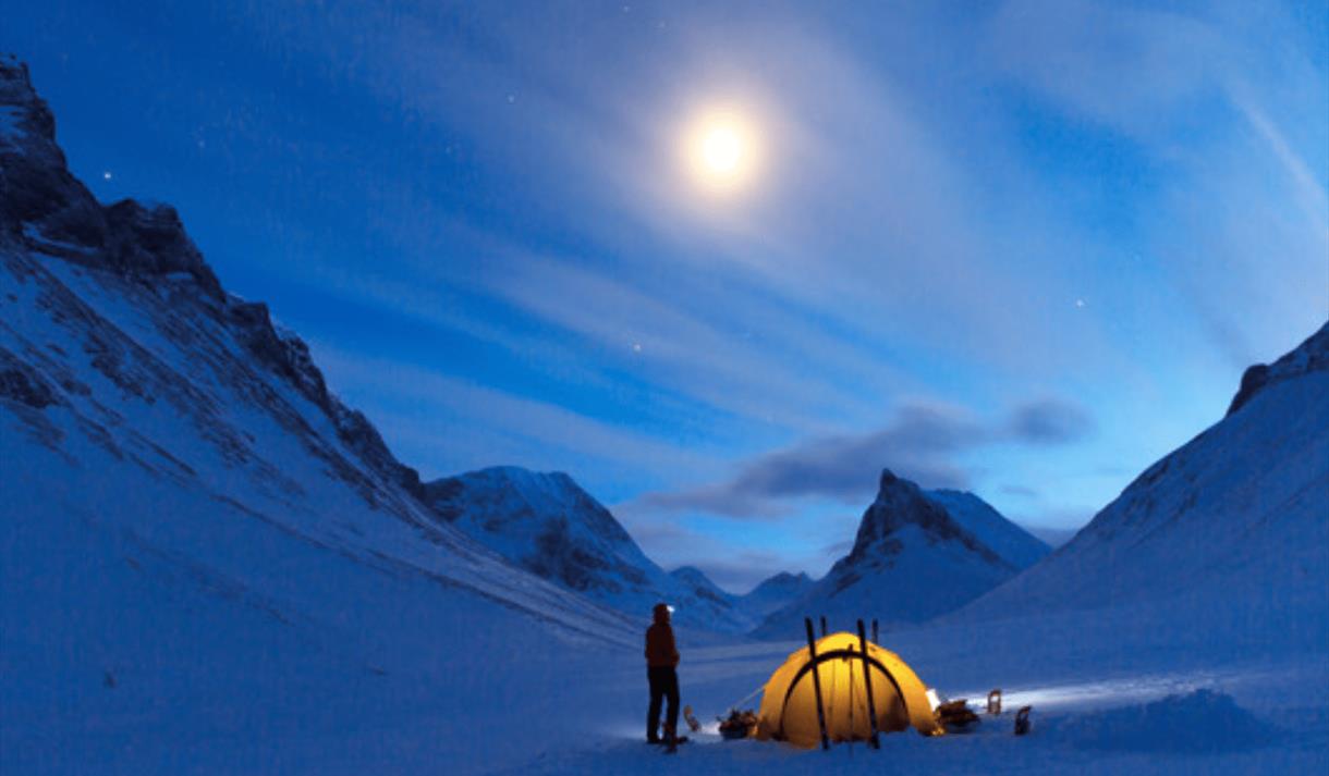 Climber outside tent early in morning before  ascending peak