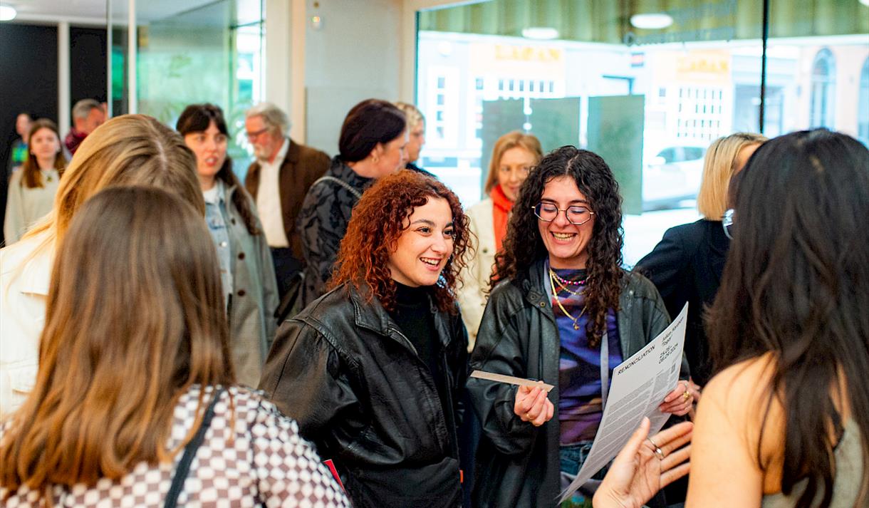 Photo of attendees mignling at an exhibition opening