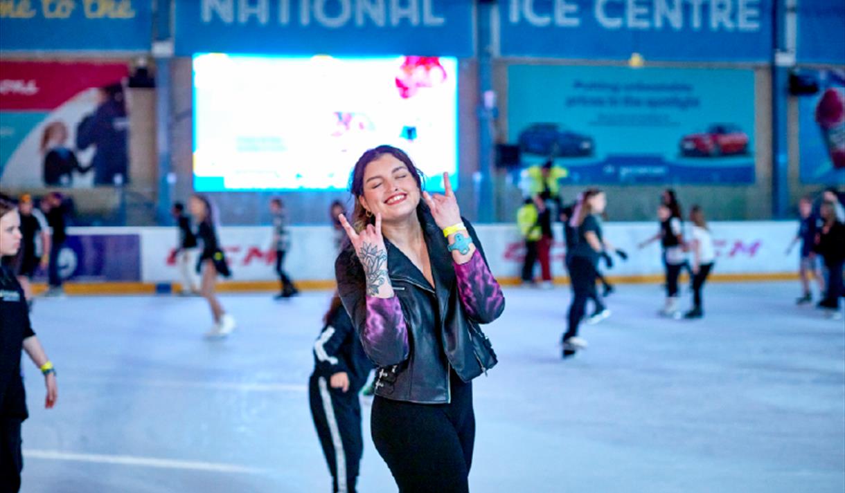 Young person skating while doing a rock sign to the camera