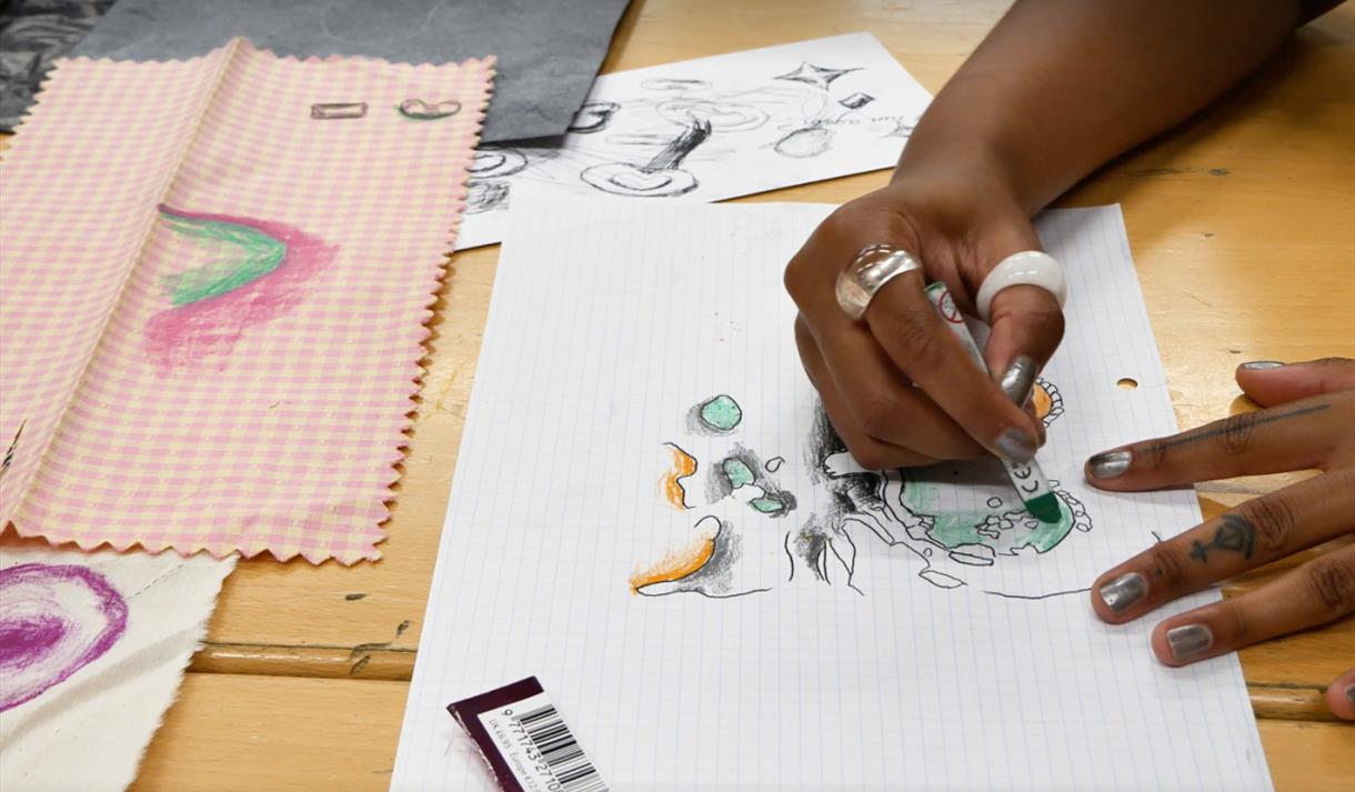 Close up photo of a hand drawing on paper with a crayon