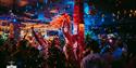 Photo of a crowded bar with fantastic dancing performers in feather headpieces, glitter faling from the ceiling and disco lights.